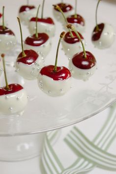 cherries with white and red toppings sit on a glass platter