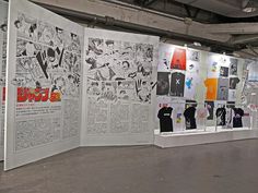 an art exhibit with comic books and t - shirts hanging on the walls in front of them