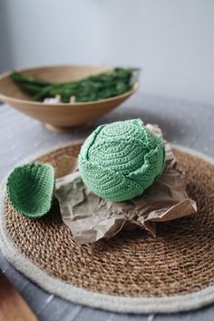 there is a green crochet hat on top of a paper bag next to a bowl