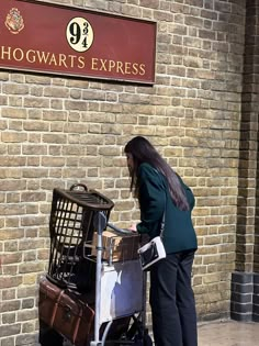 a woman standing next to a pile of luggage in front of a sign that reads hogwart's express