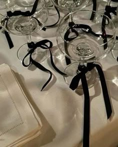 there are many wine glasses on the table with black ribbons tied around them and napkins in front of them