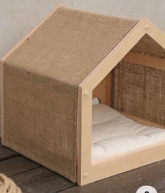 a dog house made out of burlap and wood with a white mattress inside