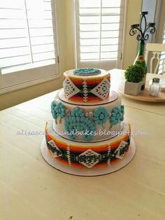 a three tiered cake on top of a wooden table next to a bottle of wine