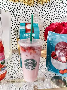 starbucks iced drink with strawberries in it on a table next to bags of coffee