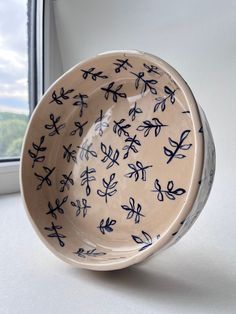 a blue and white bowl sitting on top of a window sill next to a window