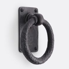 a black door handle with an oval ring on it's back end, against a white background