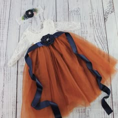 an orange and blue tutu skirt with flowers on it, sitting on a white wooden floor