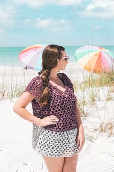 a woman standing on the beach with an umbrella in the background