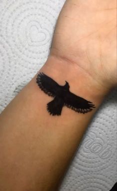 a small black bird tattoo on the wrist