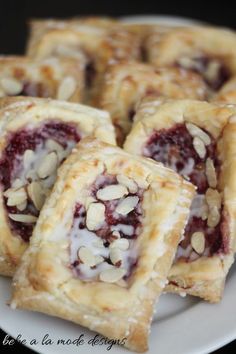 several pastries on a plate with almonds and raspberry filling, ready to be eaten