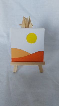 a small easel with an orange and yellow painting on it