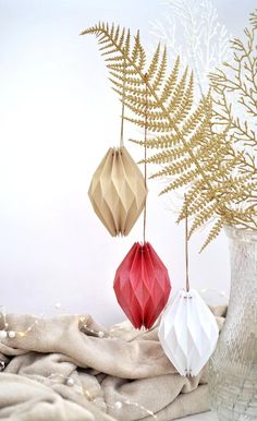 three origami flowers in vases next to each other on a cloth covered table