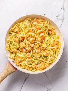 pasta with shrimp and parsley in a skillet on a marble countertop, ready to be cooked