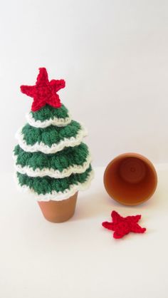 a crocheted christmas tree sitting next to a cup