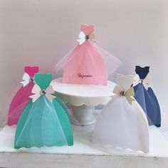 four different colored dresses are sitting on a white cake stand with the word congratulations written on it