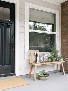 a wooden bench sitting on the side of a building next to a door and window