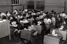 an old black and white photo of children in desks with their backs turned to the camera