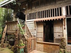 an old wooden house in the middle of some trees and plants on either side of it