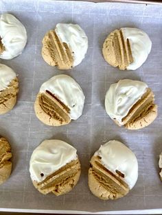 twelve cookies with white frosting on a baking sheet