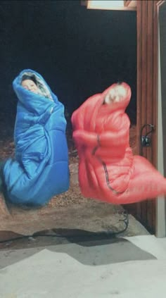 two people in sleeping bags sitting on the ground next to a fire hydrant and door