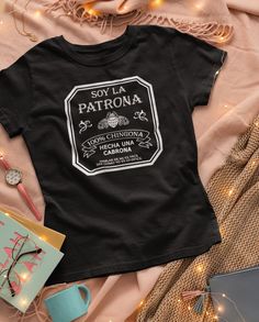 "The \"La Patrona\" shirt/sweatshirt is a perfect choice for any strong, confident, and proud Latina woman who wants to show off her roots and her feminist beliefs. This Mexican clothing item is a symbol of empowerment and resilience, designed specifically for women who refuse to back down and are not afraid to take charge of their lives. This chingona shirt is a beautiful and vibrant expression of Mexican culture, featuring bold and colorful graphics that showcase the beauty and strength of Mexican women. It is perfect for any occasion, including Dia de las Madres (Mother's Day) when you want to give a regalo para mama (gift for mom) that truly reflects her identity as a Mexican mom. The La Patrona shirt is an ideal choice for any strong-willed Latina who wants to show off her boss lady a Mexican Women Fashion, Mexican Shirts Woman, Mexican Shirts Sayings, Mexican T Shirts Design, Latina T Shirt Ideas, Latina Af Shirt, Educated Latina Shirt, Mexican Top, Wednesday Dress