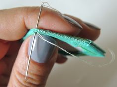 a person is holding a piece of green fabric with needles attached to the tip of it