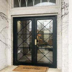 a welcome mat on the front door of a building with glass doors and wrought iron windows