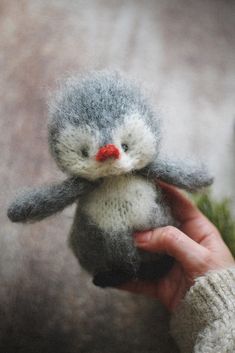 a hand holding a small gray and white stuffed animal