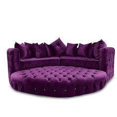 a purple round couch with lots of pillows on it's back and sides, sitting in front of a white background