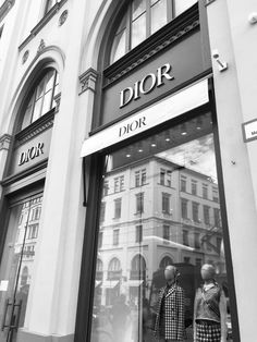 two mannequins in front of a dior store on a city street