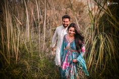 a man and woman walking through tall grass