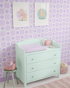 a baby's room with pink and purple wallpaper, a crib and two pictures on the wall