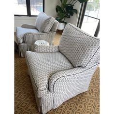 two couches with pillows on them in a living room next to a potted plant