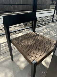 a chair sitting on top of a sidewalk next to a rail road track with train tracks in the background