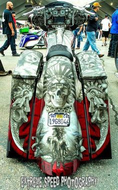 an extreme speed motorcycle parked in a parking lot with people walking around and looking at it