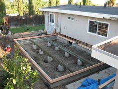 an unfinished backyard with concrete being poured into the ground and plants growing in the yard