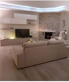 a living room filled with furniture and a flat screen tv mounted on the wall next to a fire place