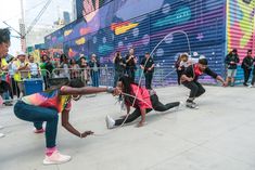 some people doing tricks on their skateboards in front of a wall with colorful graffiti