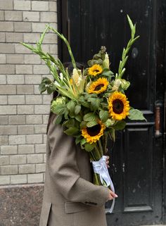 a man walking down the street holding a bouquet of sunflowers