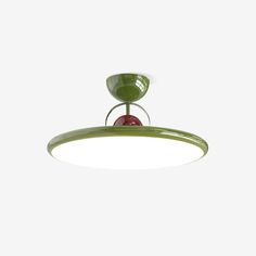 a green ceiling light with a red ball hanging from it's center point, on a white background