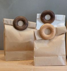 three brown paper bags with donuts on them sitting on a wooden table next to each other