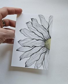 a hand holding a piece of paper with a flower on it