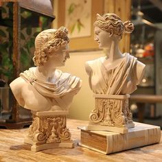 two marble busturines sitting on top of a wooden table