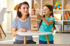 a woman and girl playing with wooden blocks