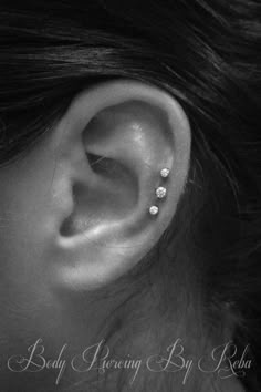 a woman's ear with three piercings on it