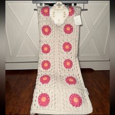 a crocheted blanket with pink and yellow flowers is hanging on a clothes rack