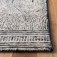 a black and white area rug on a wooden floor with wood floors in the background