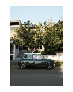 an old car is parked on the side of the road in front of a house