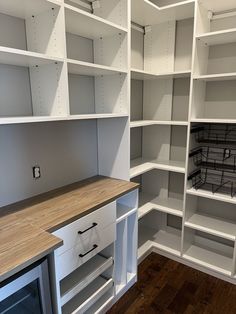 an empty room with white shelving and wooden counter tops in the center, along with shelves on both sides