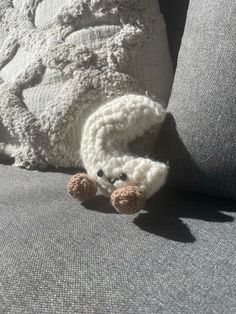 a stuffed animal laying on top of a gray couch next to a white throw pillow